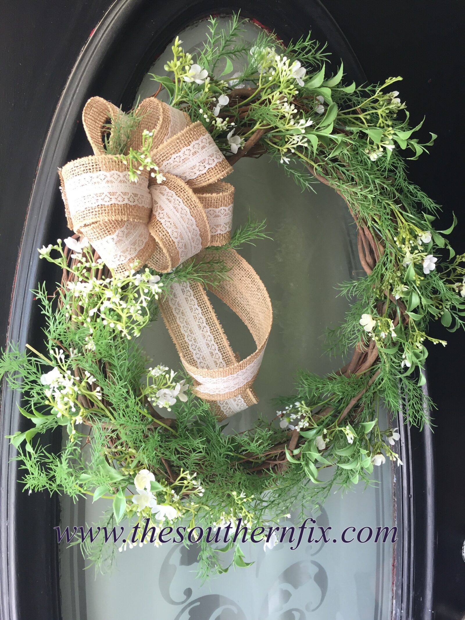 DIY Farmhouse Wreath: grapevine wreath with green foliage, white flowers, burlap and lace bow